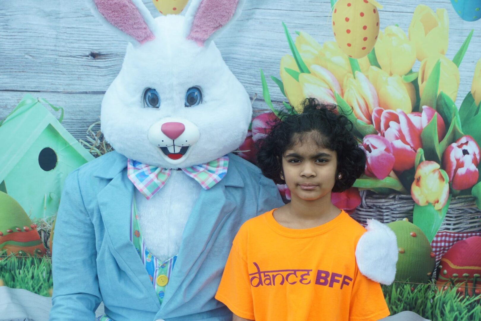 The bunny mascot and a girl in an orange shirt and pink earrings