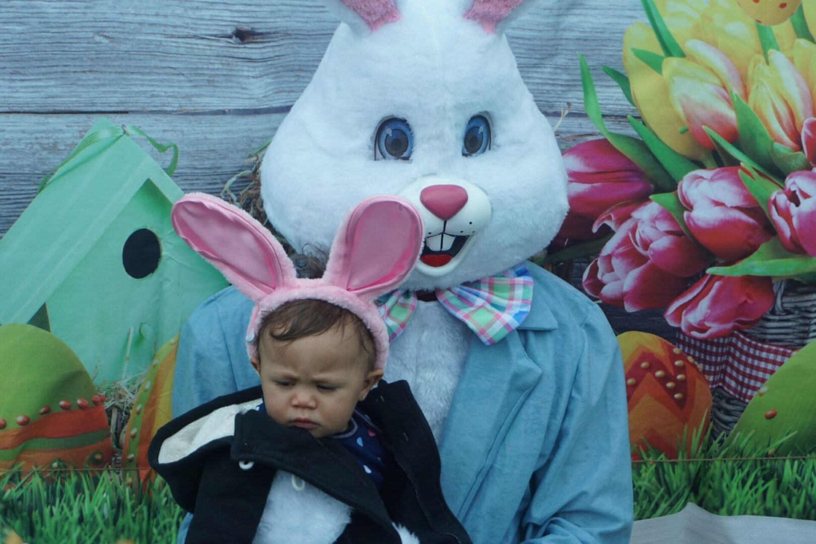 The bunny mascot holding a baby with bunny ears