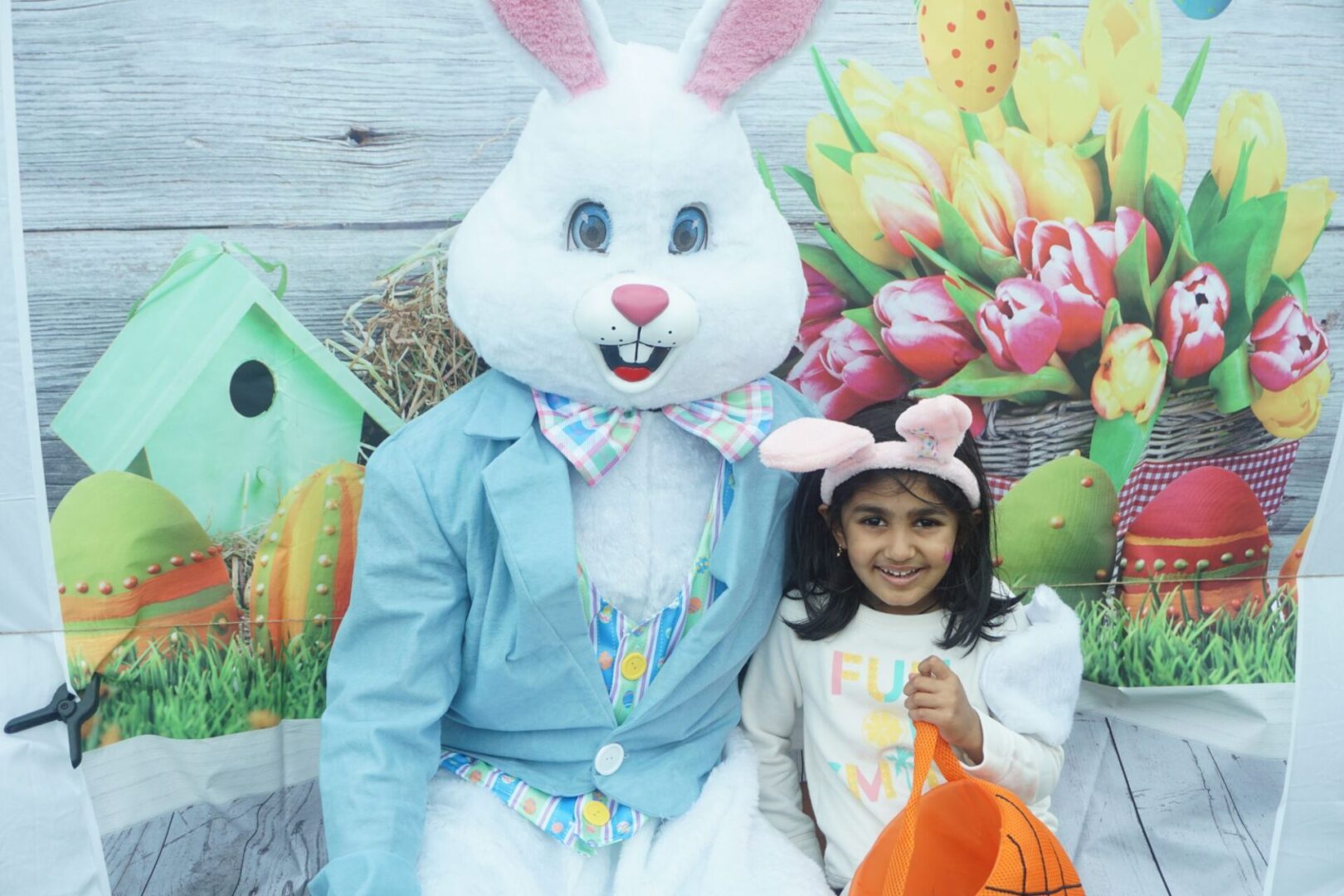 The bunny mascot together with a girl with pink bunny ears and orange basket bag