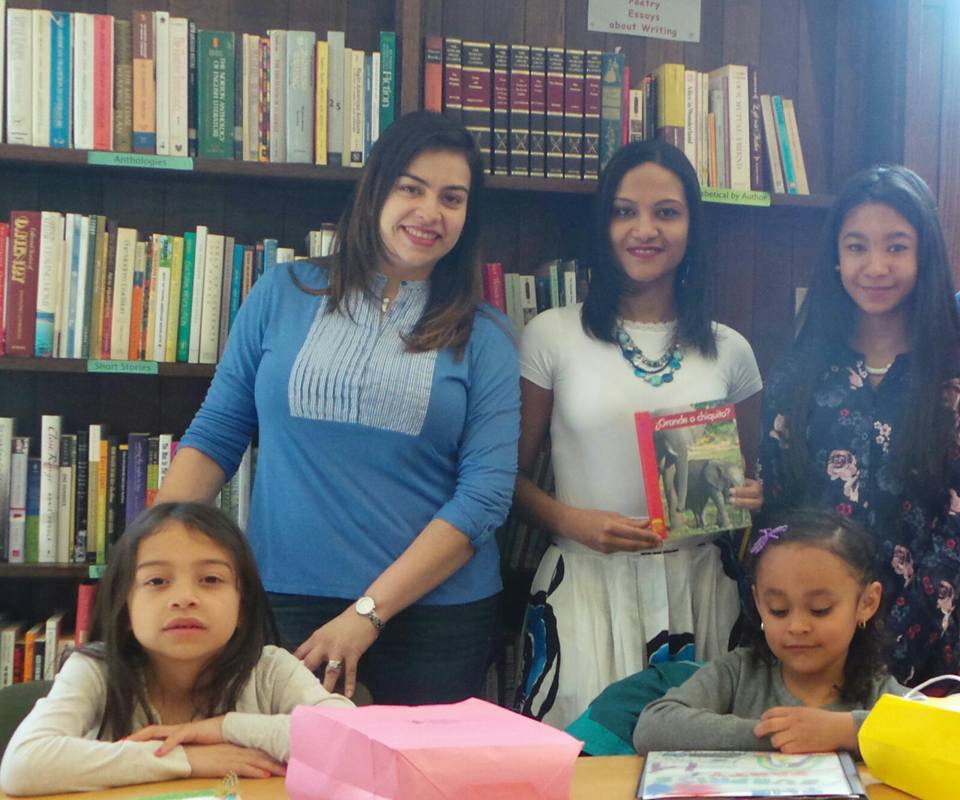 Three women with one of them holding a book and two young girls, cropped