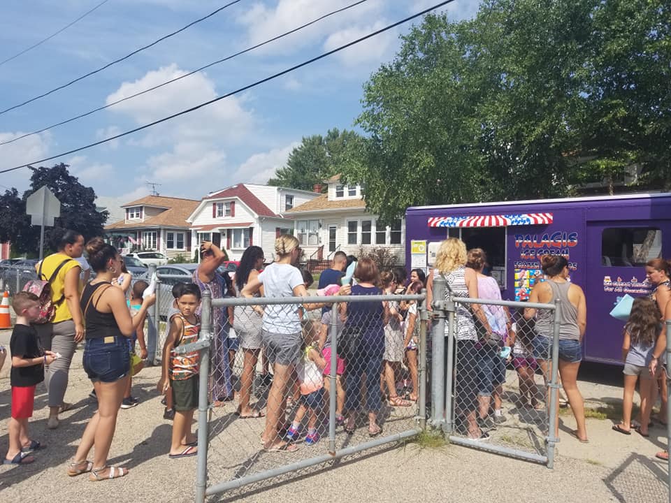 Adults and children line up at a purple ice cream truck
