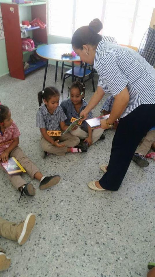 Another woman giving a book to a girl sitting on the floor
