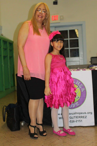 A woman wearing a pink top and a little girl in a pink dress and headband