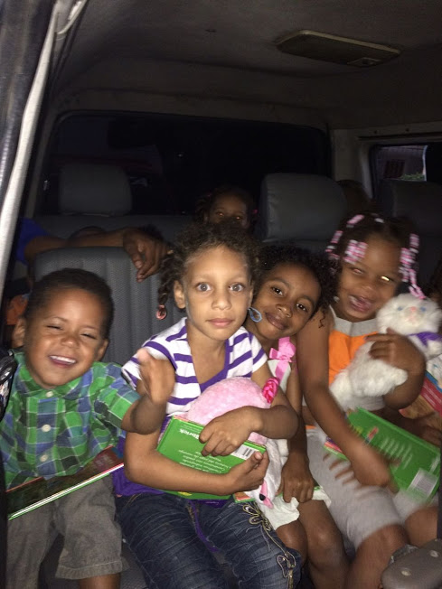 Children in the car, smiling and holding their toys and books