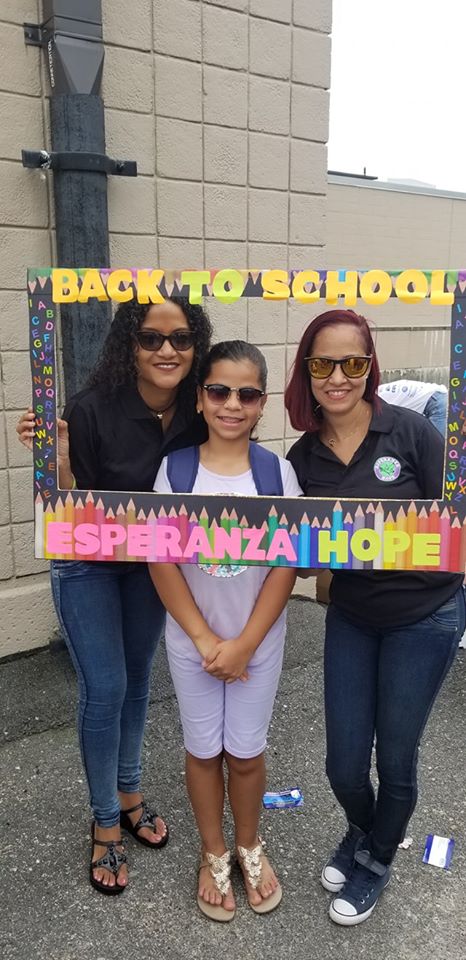 Two female staff and a girl, all wearing sunglasses and holding a back to school frame