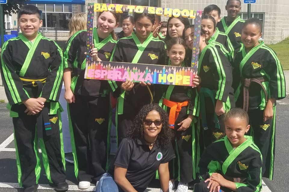 A female staff and a group of children athletes posing with the back to school frame