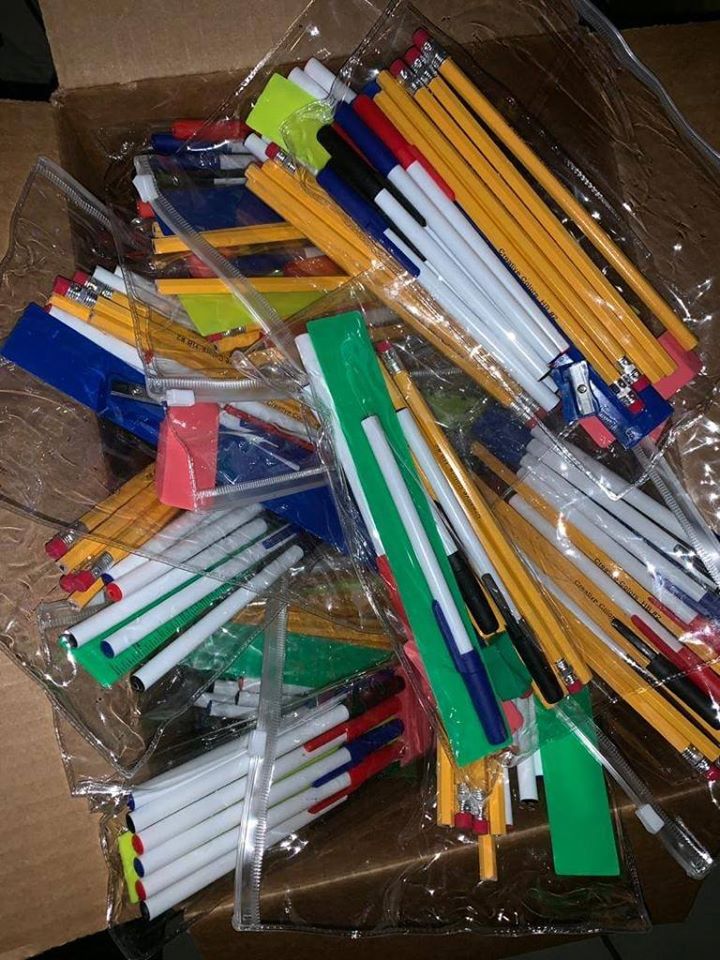 An open box full of pencils and pens in clear zip lock pencil cases