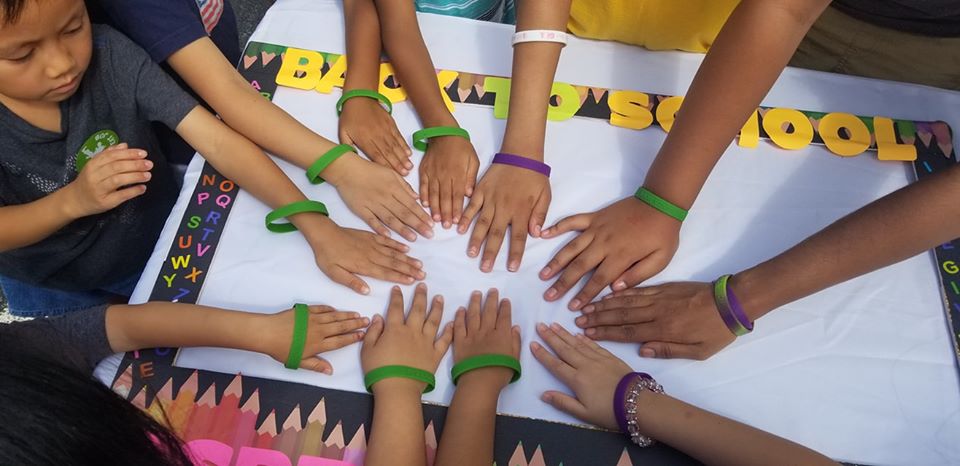 Children showing their hands wearing the colored bracelets we gave