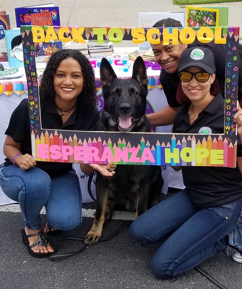 Three female staff together with a black dog and posing with a back to school frame