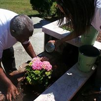 A man planting a flower and a woman watering it