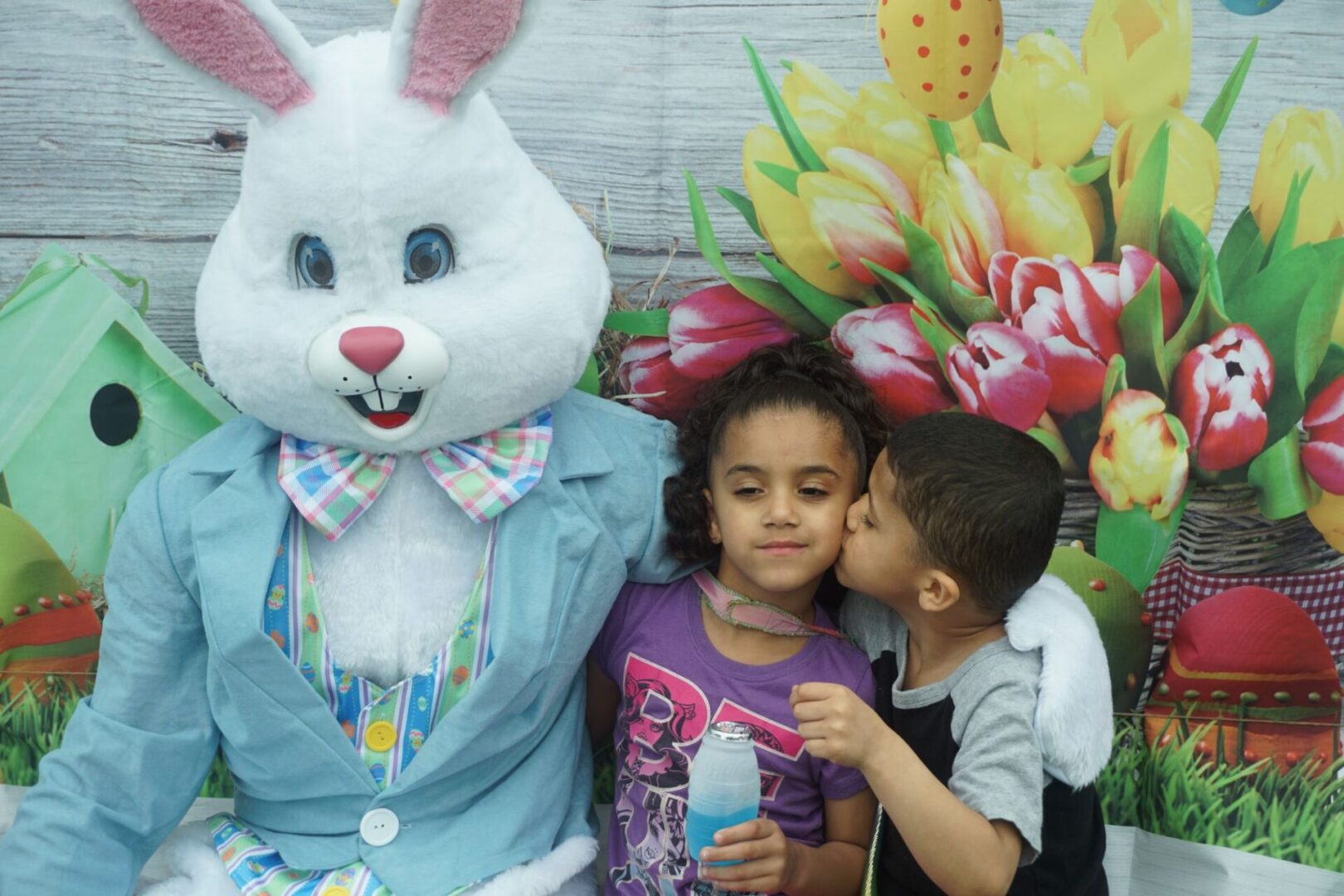 The bunny mascot together with a girl holding a drink and a boy kissing the girl on the cheek (1)
