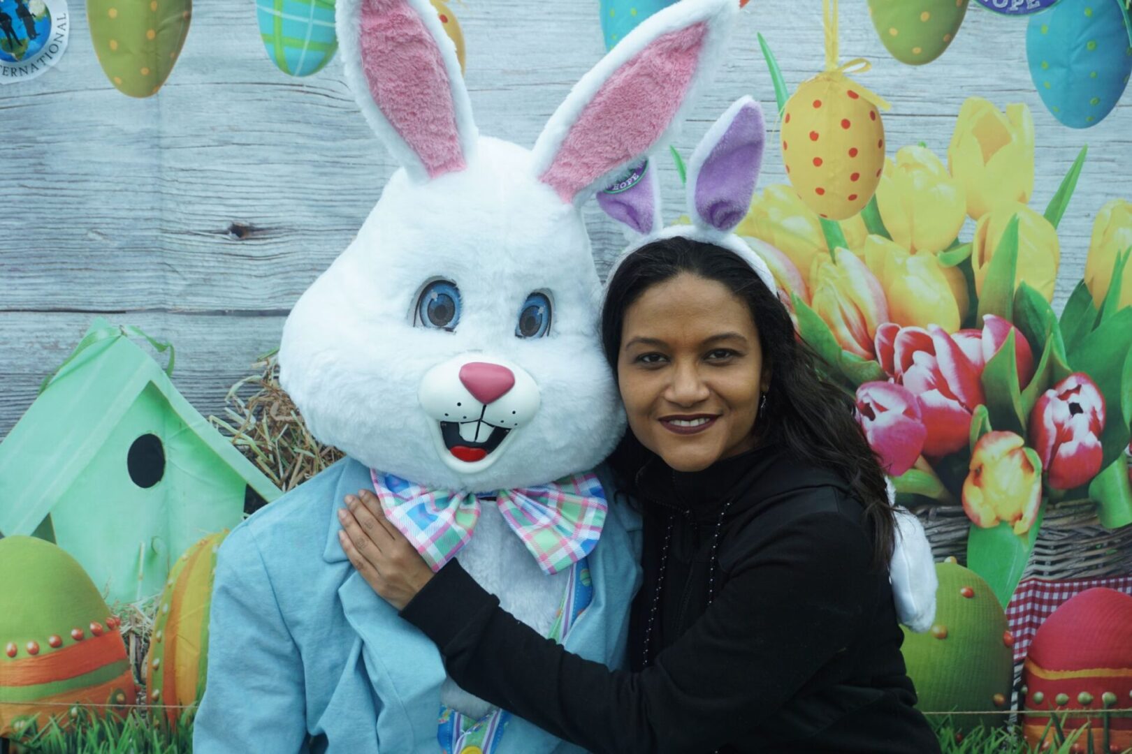 A female staff with bunny ears with her arms around the bunny mascot