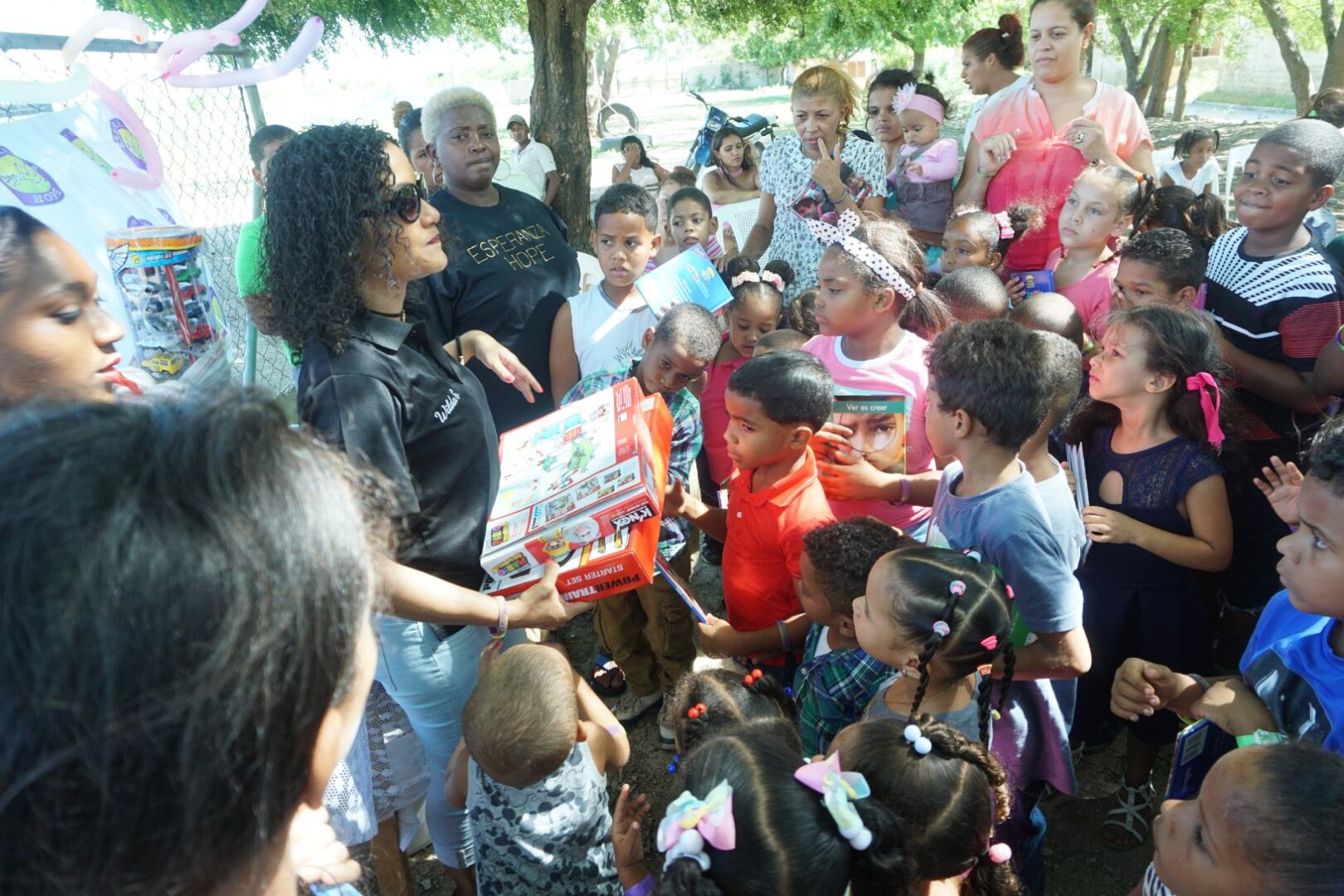 The children looks at our female staff holding two boxes of toys