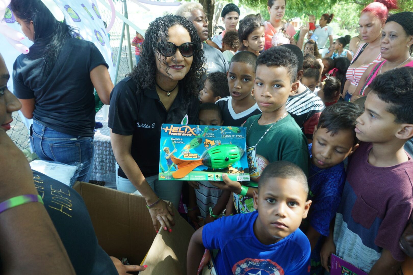 A female staff and a boy holding a box of a Helix toy, surrounded by a crowd