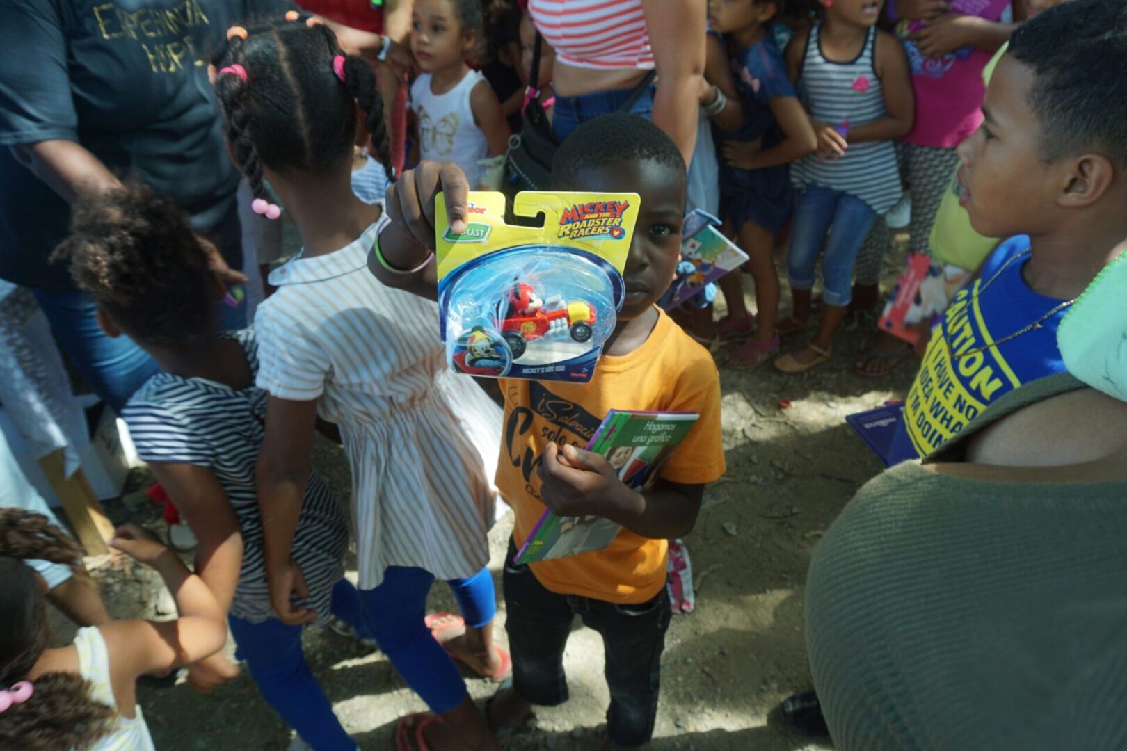 A child carrying a book and showing the toy car he got