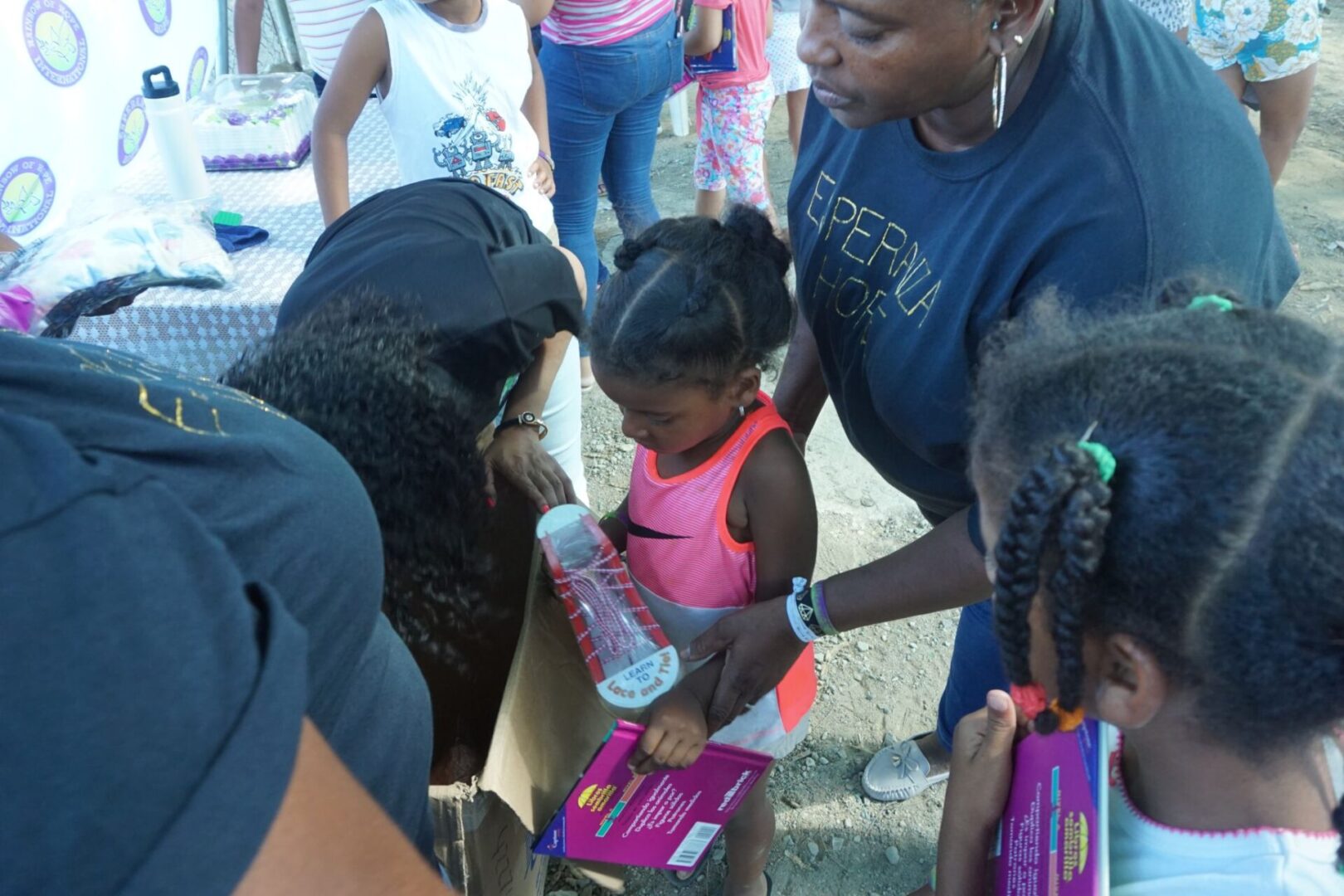 A female staff holding a little girl and another one gets a toy from a box