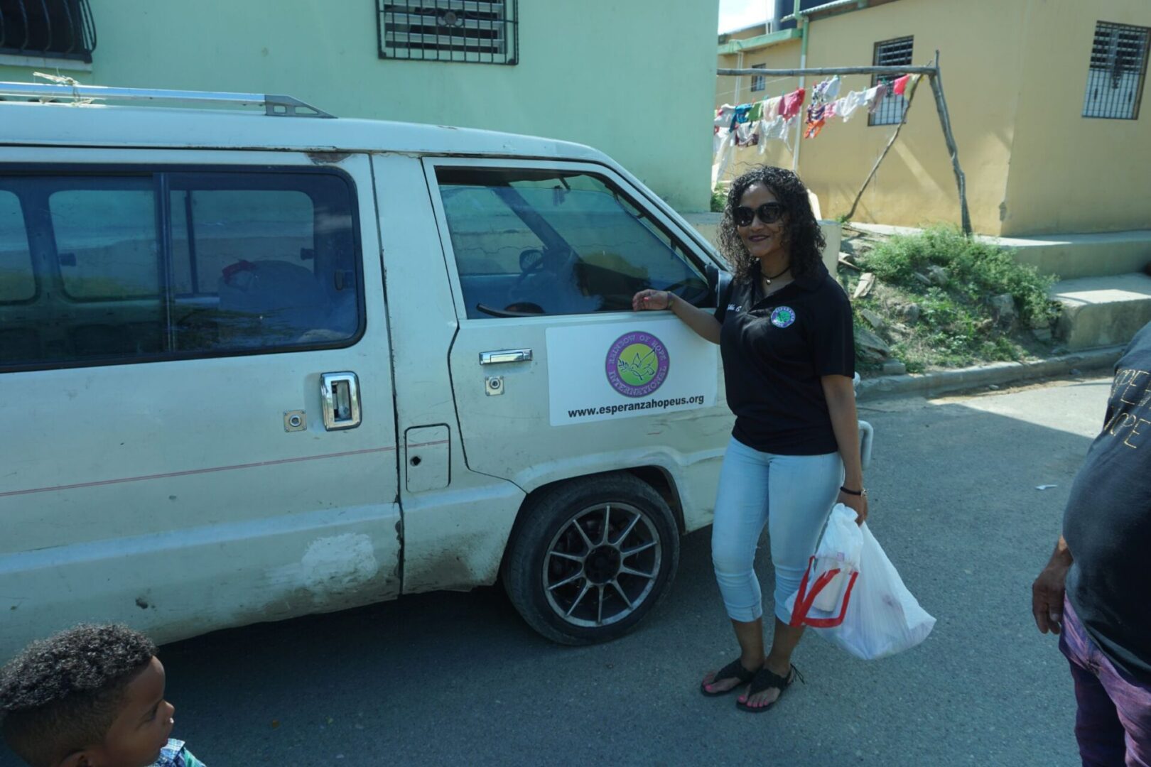 A female staff holding a white plastic bag in front of our vehicle