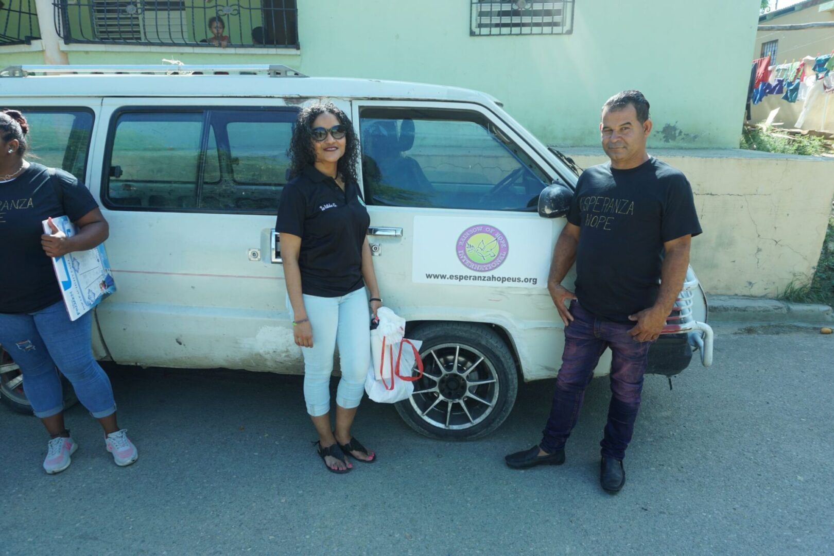 A male and female staff in front of Esperanza-Hope’s white van