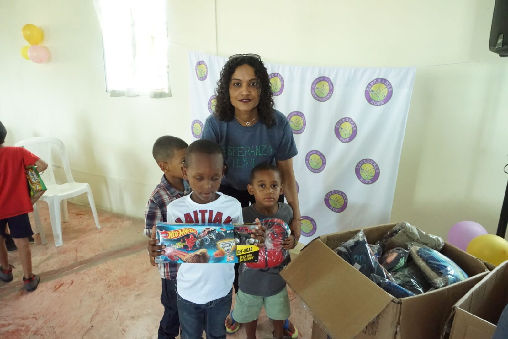 A female staff together with three boys holding toys
