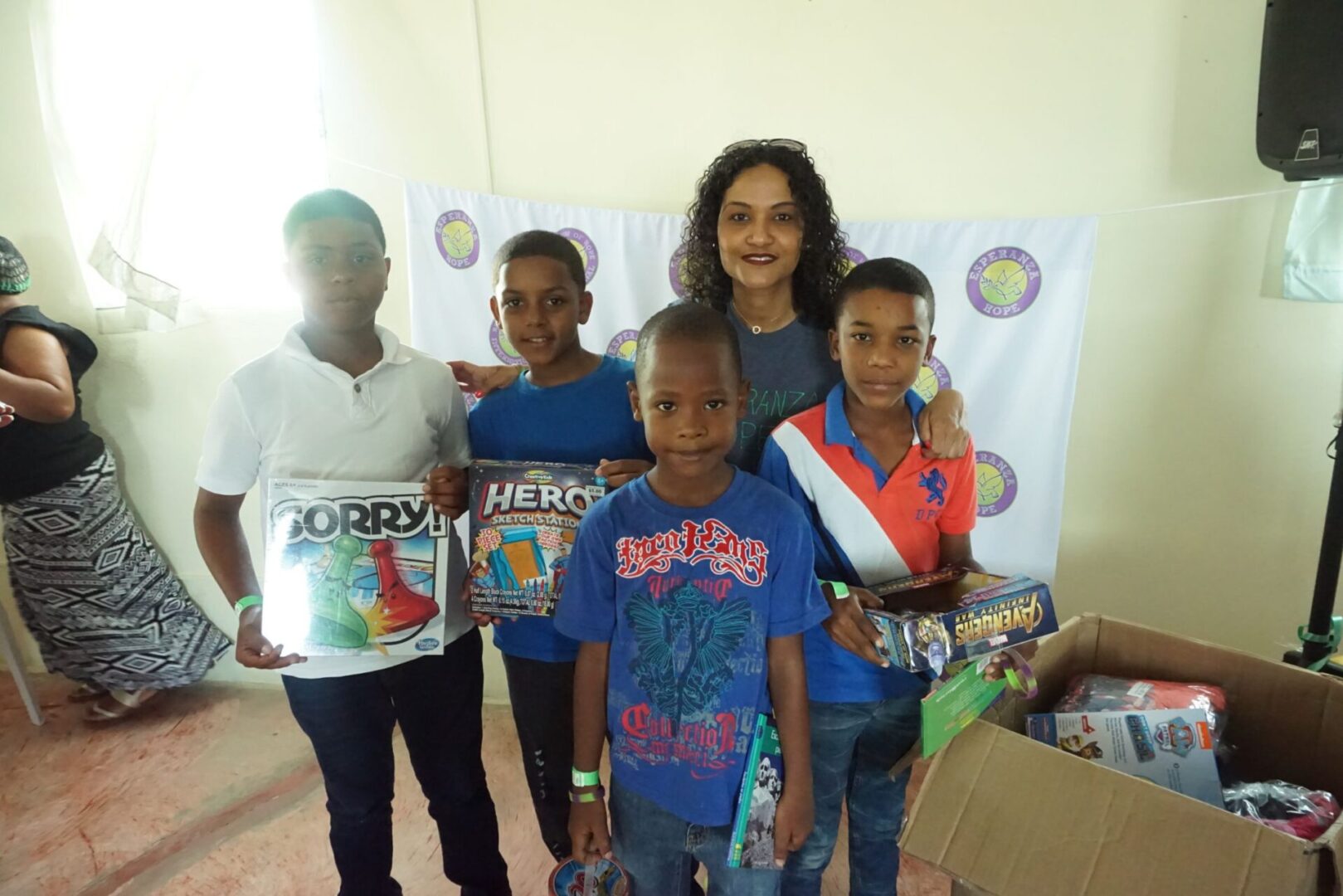 A female staff and four boys holding boxes of toys