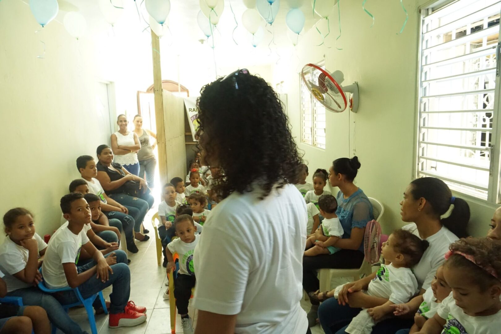 A woman in a small room in front of the children and their mothers