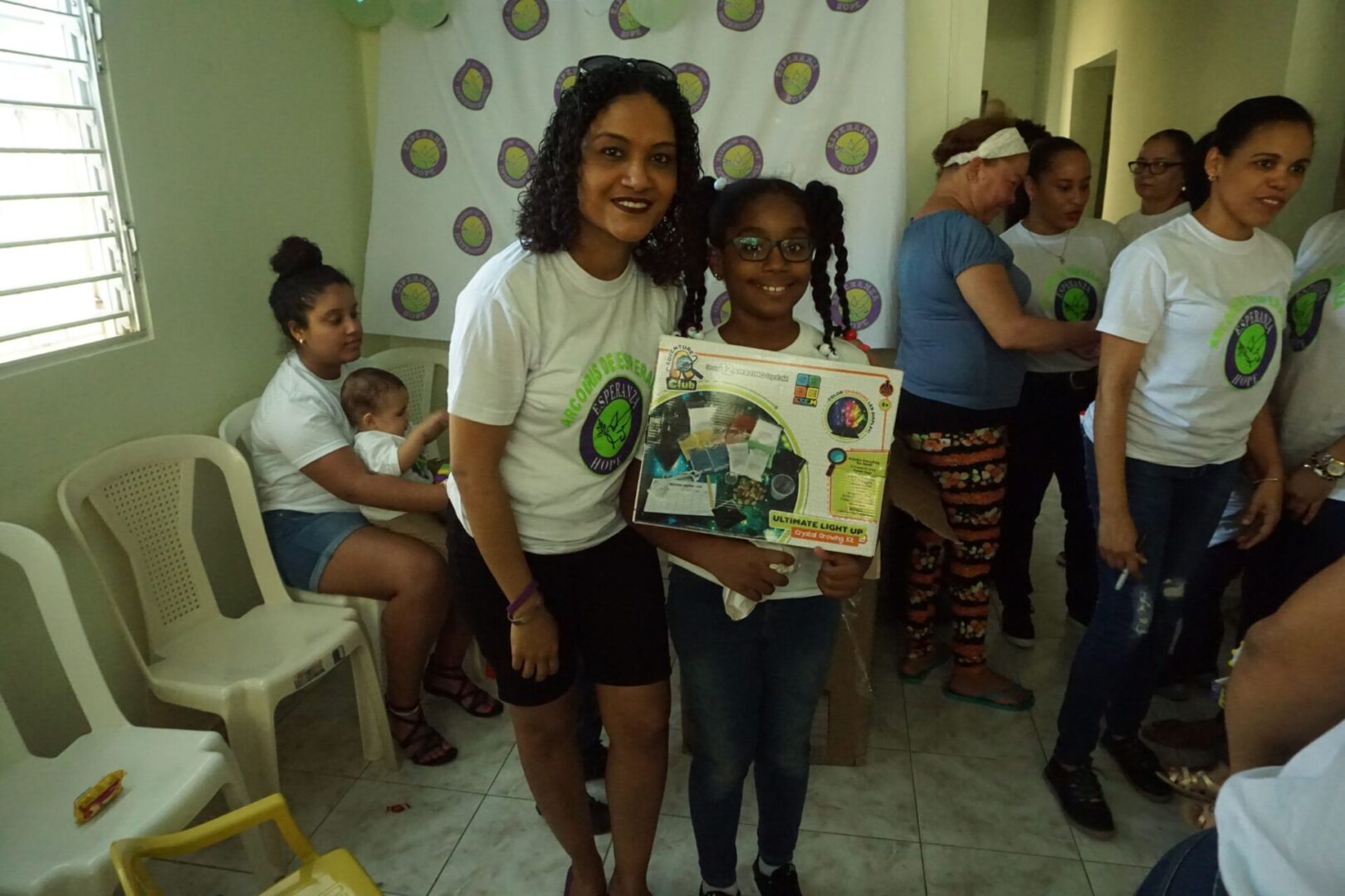 A female staff and a girl in eyeglasses holding a box of toy