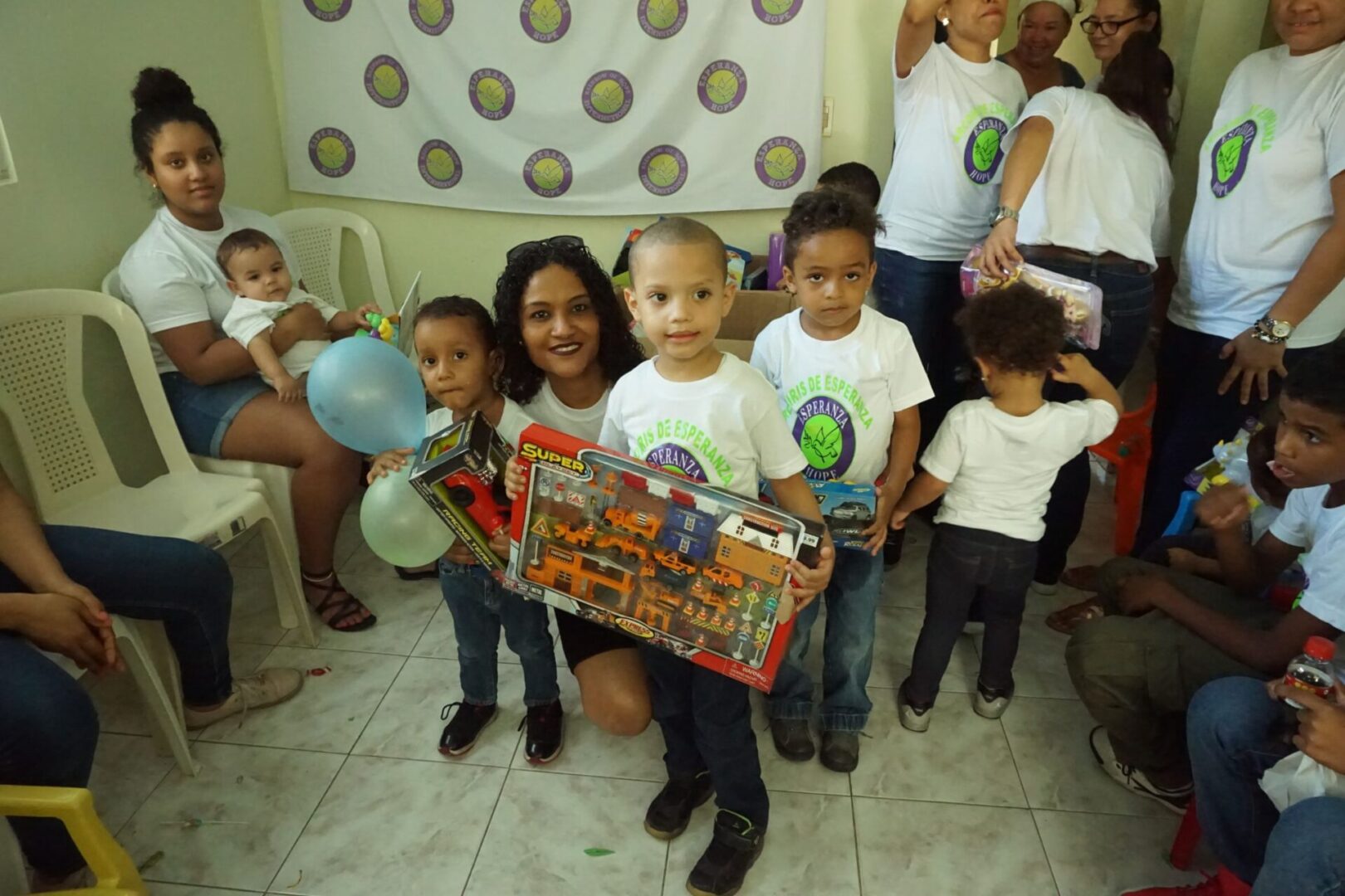 A female staff and three little boys each holding their box of toy car