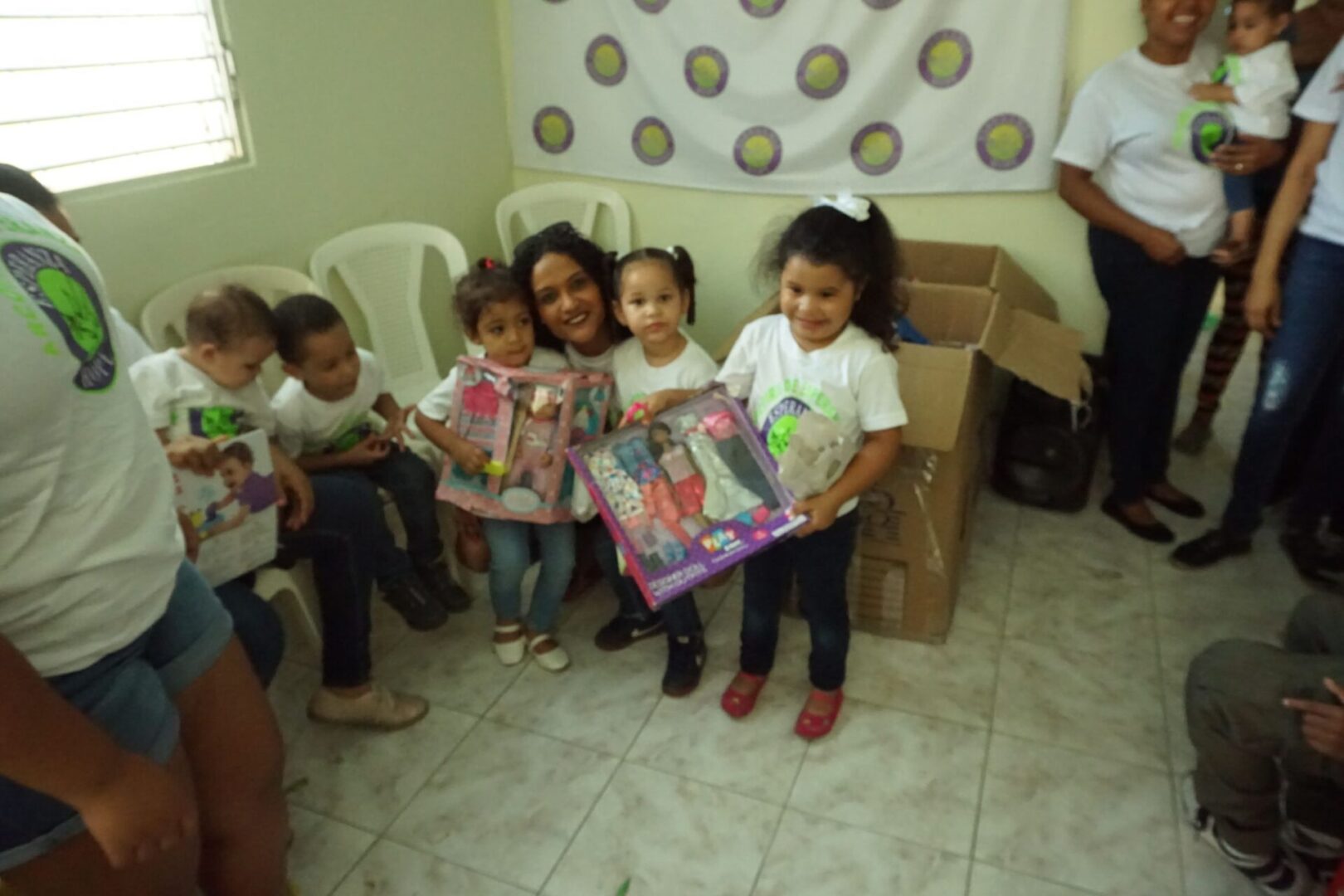 A female staff and three little girls holding their dolls (blurred)