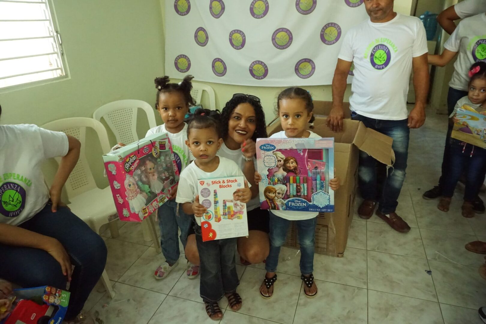 A staff and three little girls holding their boxes of toys; box at the back