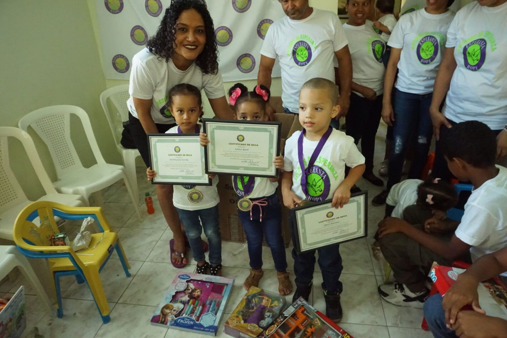 Two little girls and a little boy wearing their medals and showing their certificates
