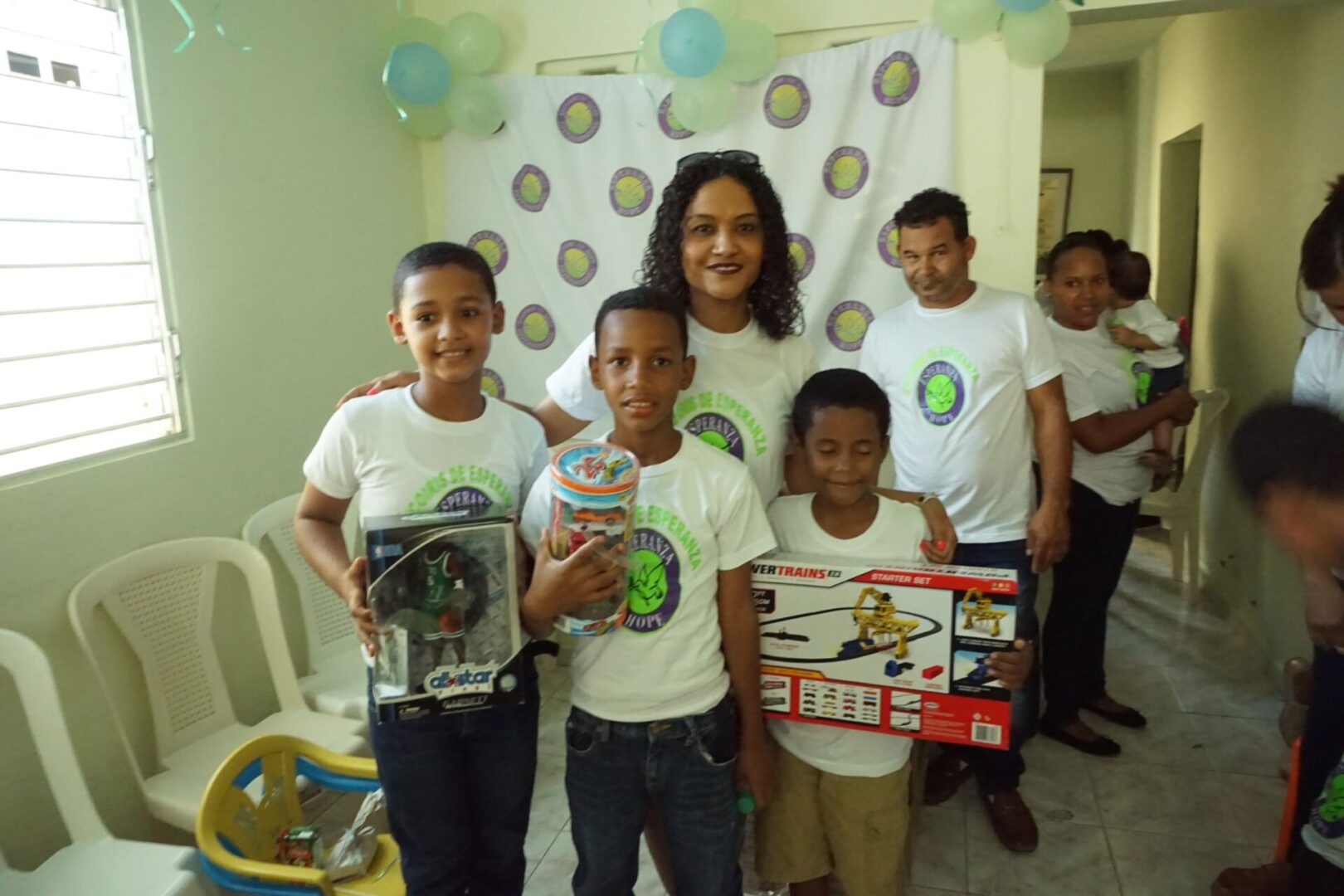 Three boys holding their boxes of toys; staff and other people at the back
