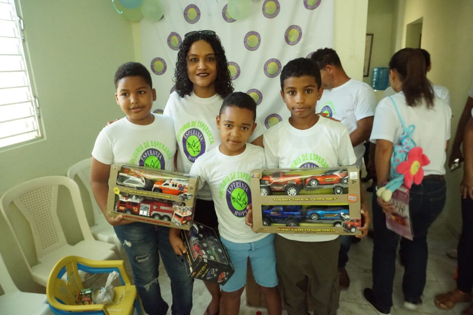 A female staff and three boys each holding their box of toy cars