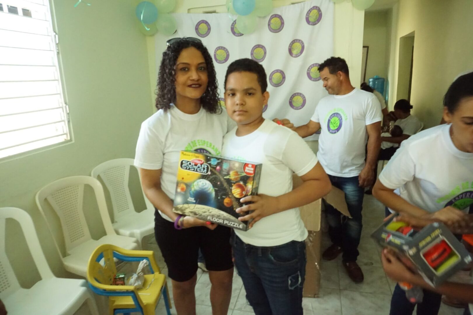 A staff and a boy holding a box of solar system toy