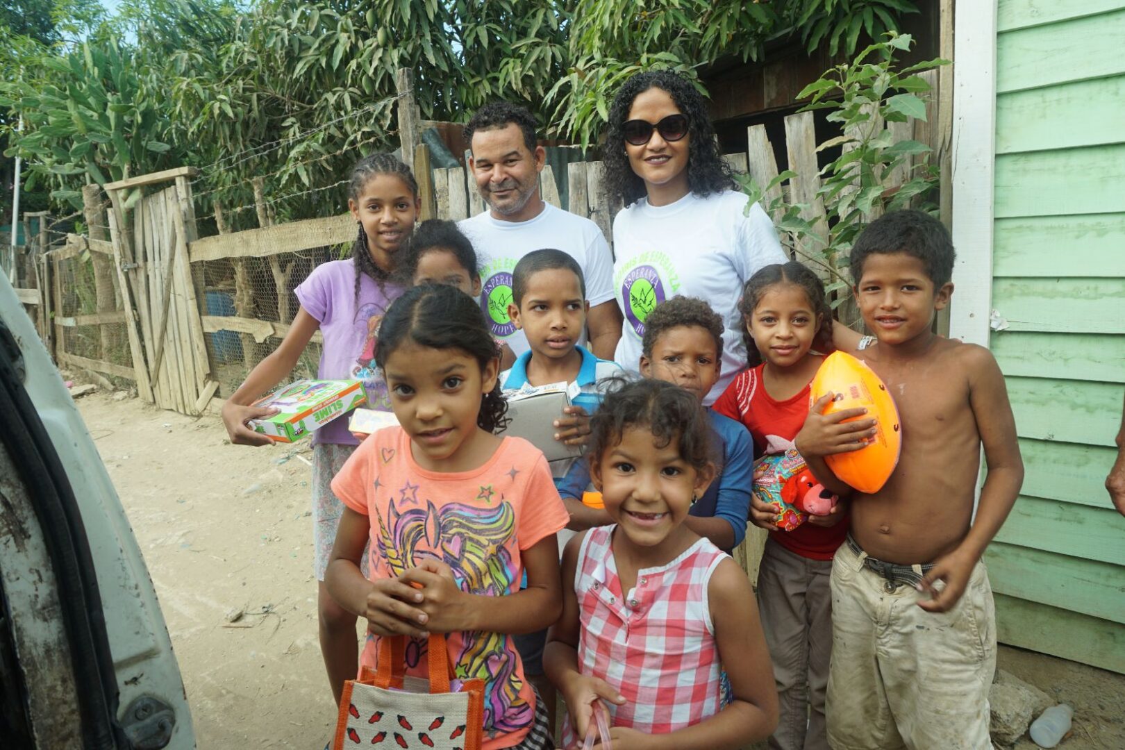 Two staff and a group of children smiling and holding their toys