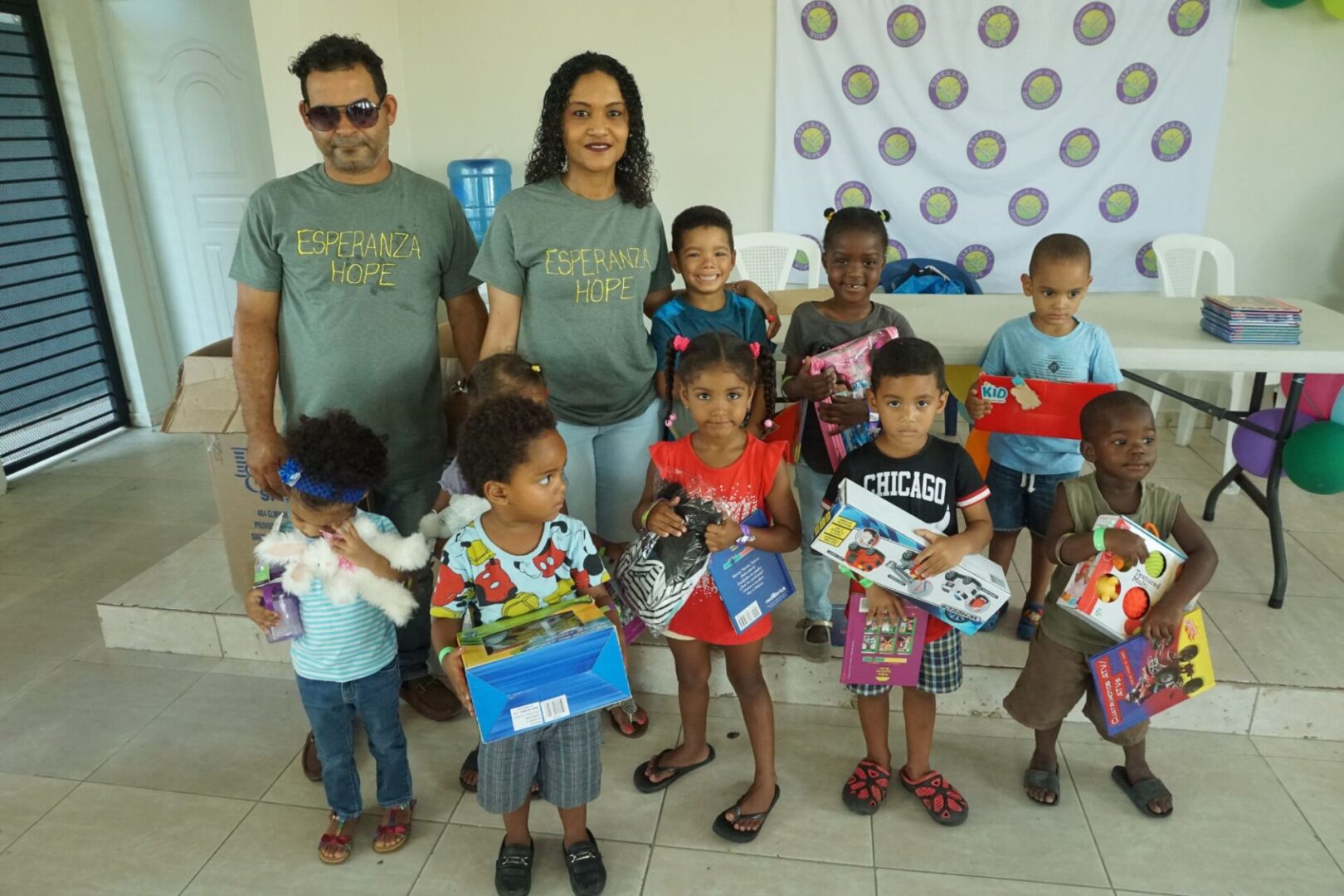 A male and female staff together with the group of young girls and boys who received toys, close-up