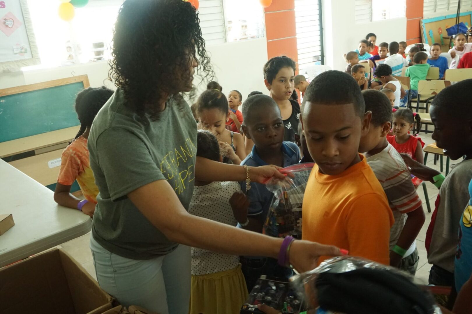 A female staff giving out clothes to children in a classroom (scaled)