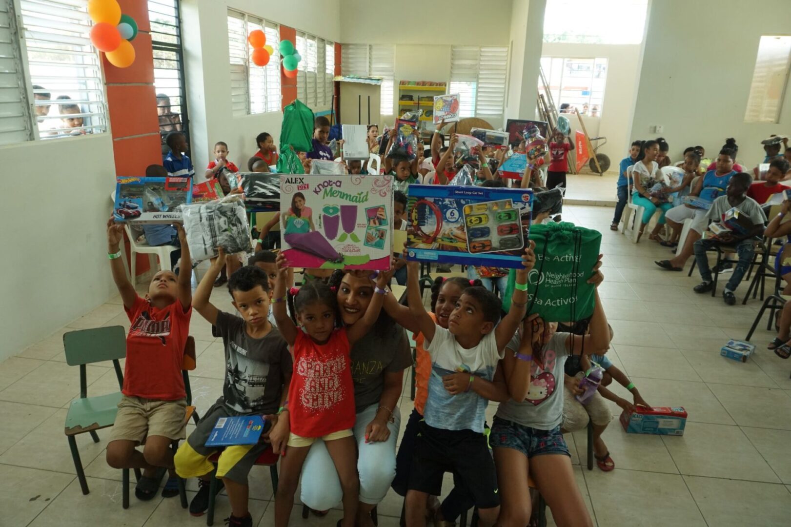 Children on the left side of the classroom holding their toys up while sitting