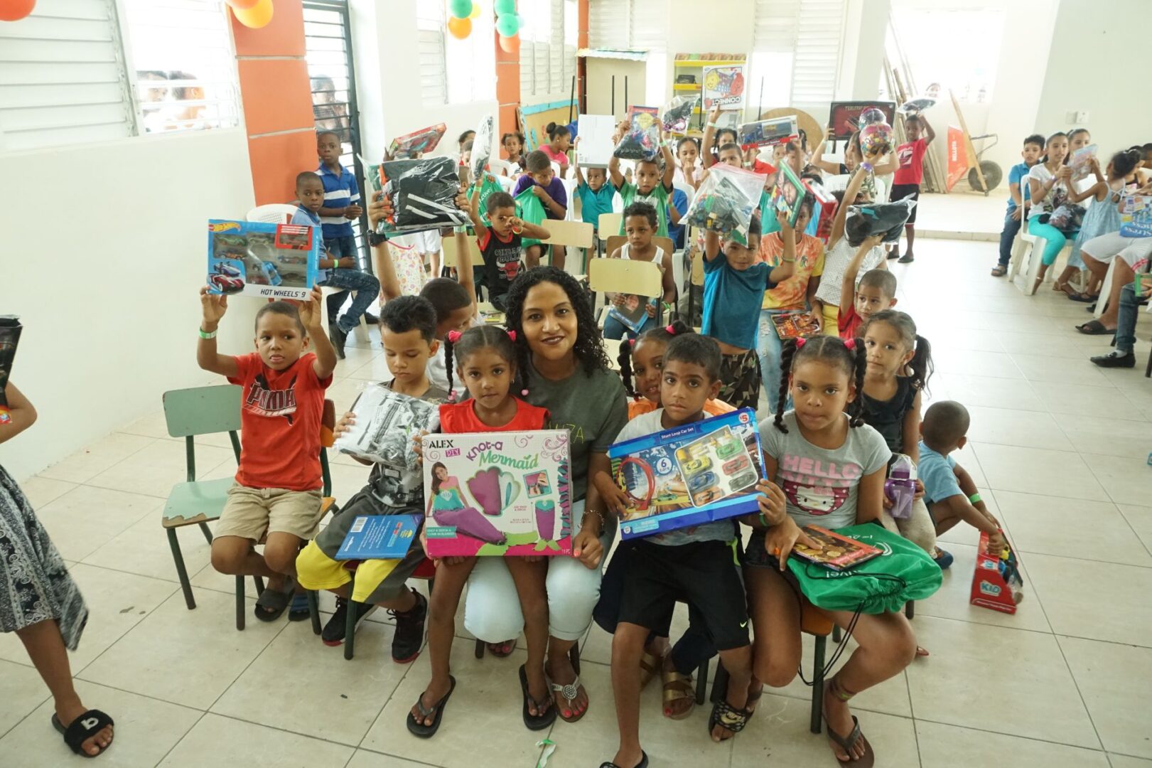 Children on the left side of the classroom holding their toys up while sitting, 2
