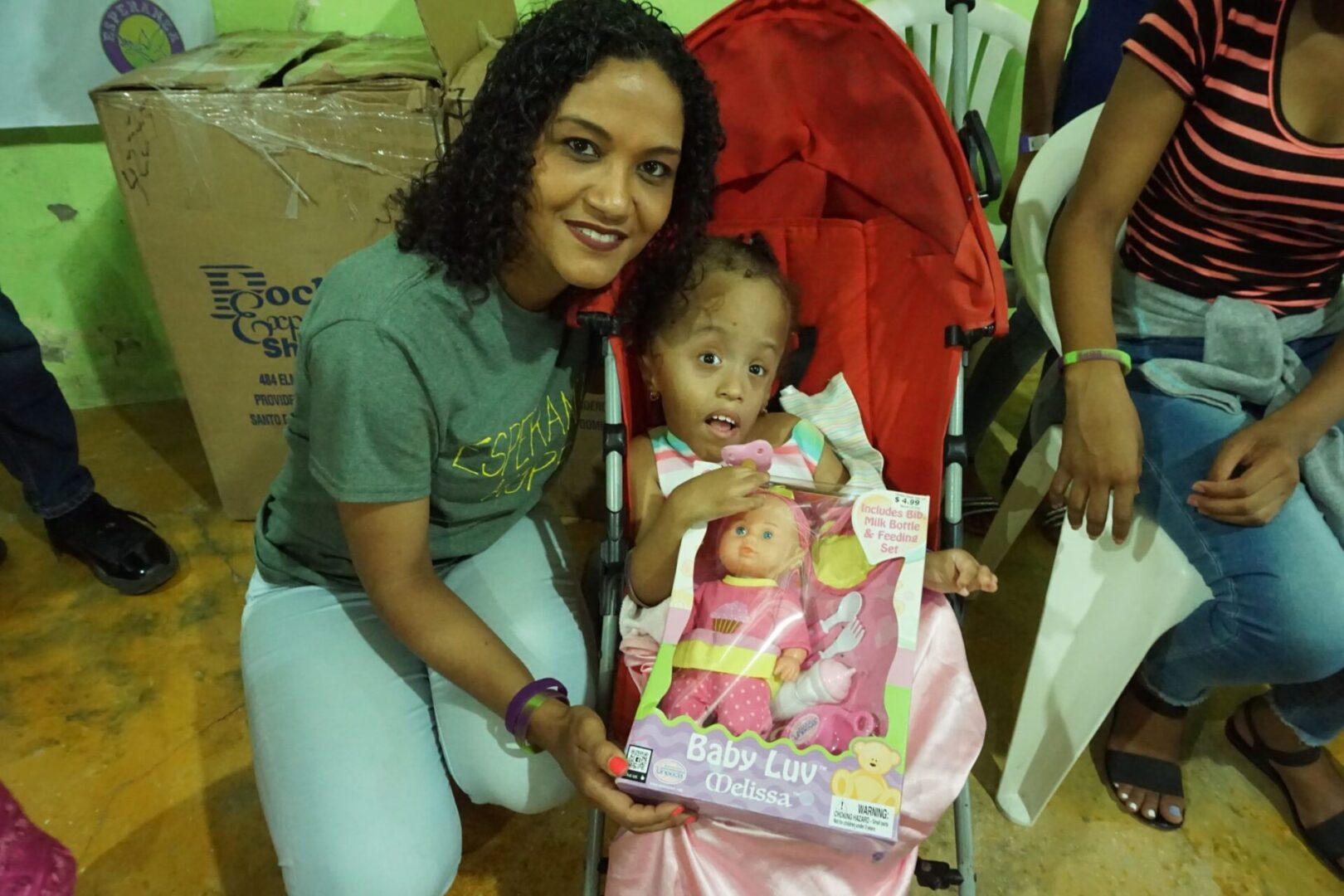 A female staff and a girl in a stroller holding a baby doll