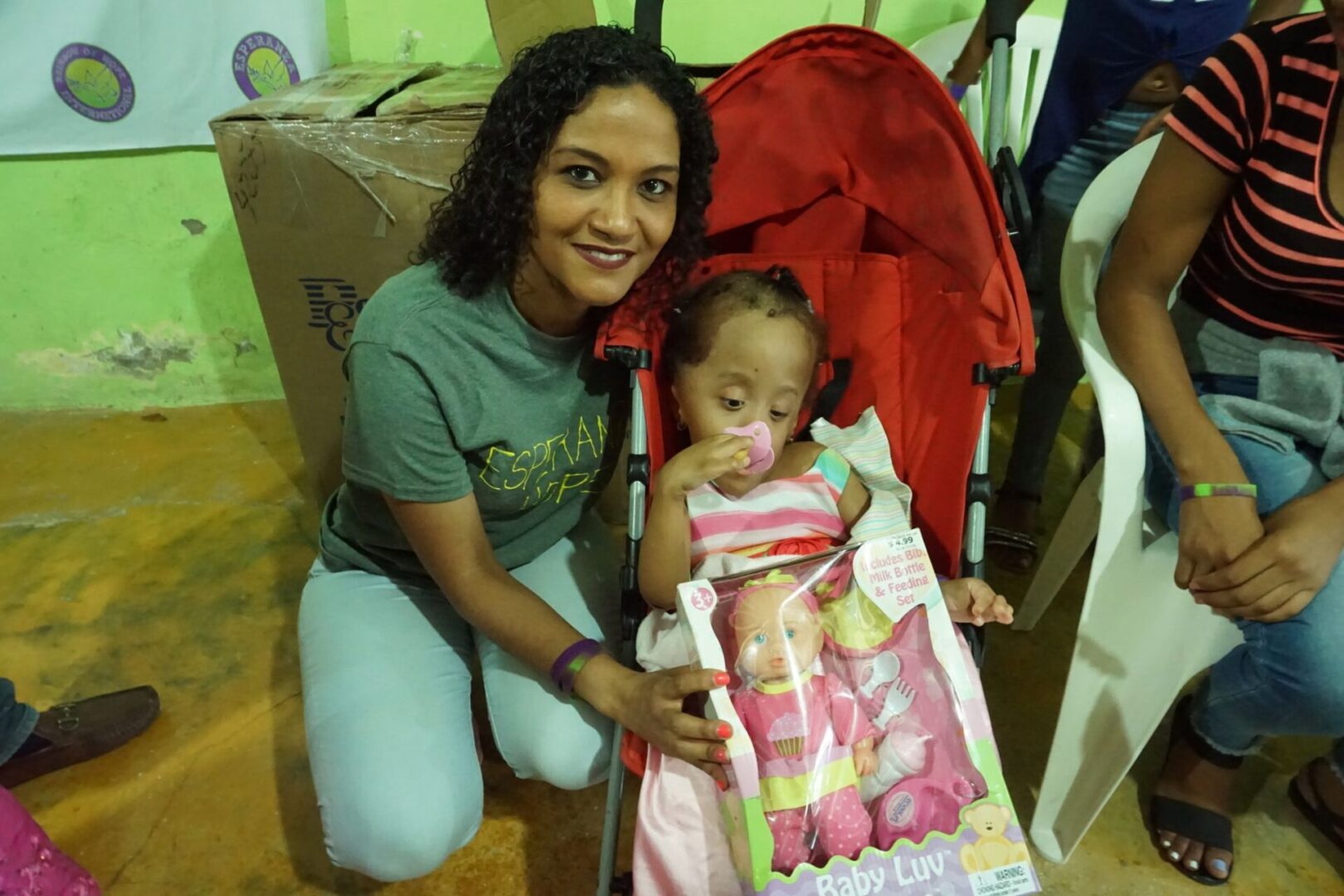 A female staff and a girl in a stroller holding a baby doll, 2
