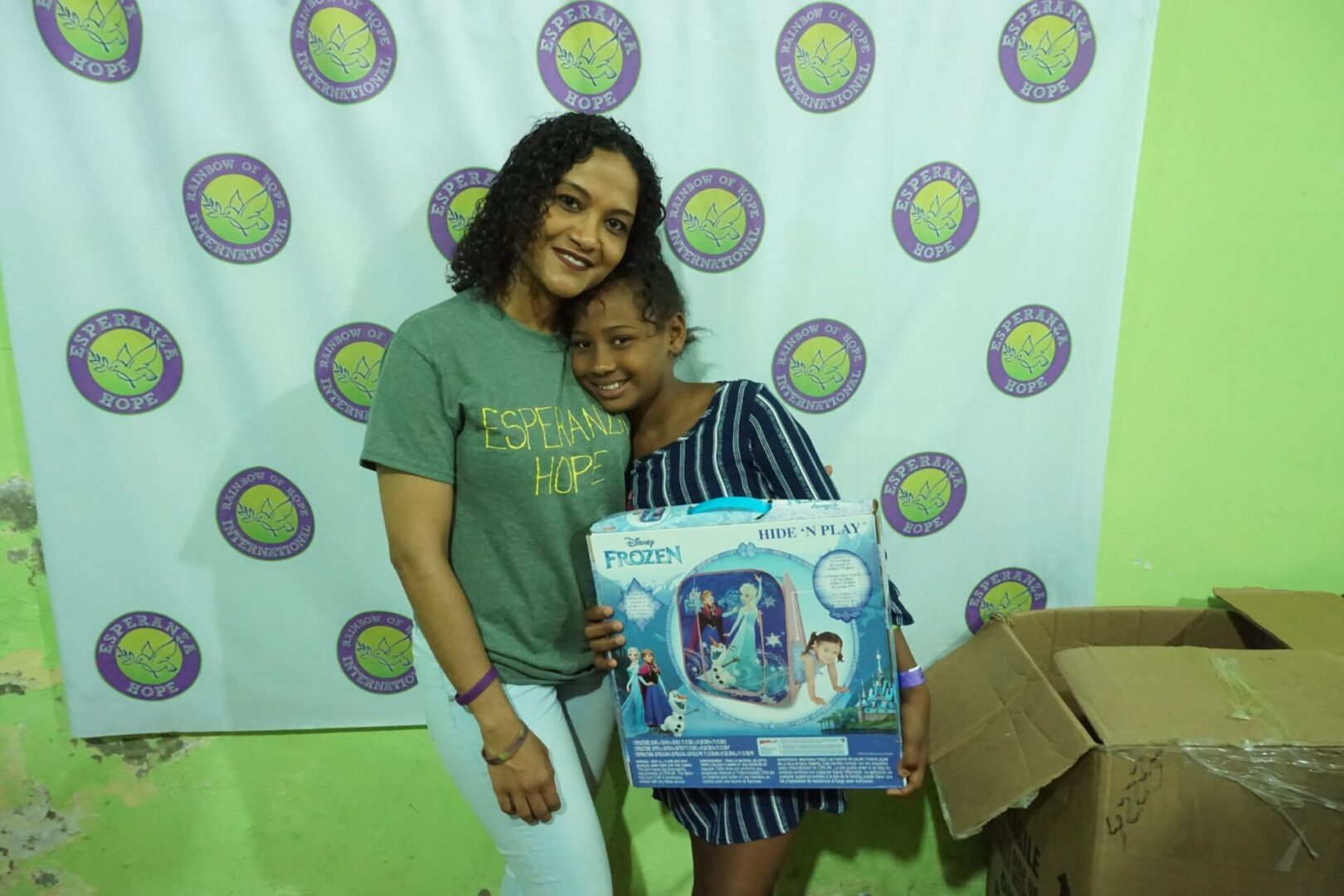 A staff and a girl in a blue dress holding a box of Frozen toy