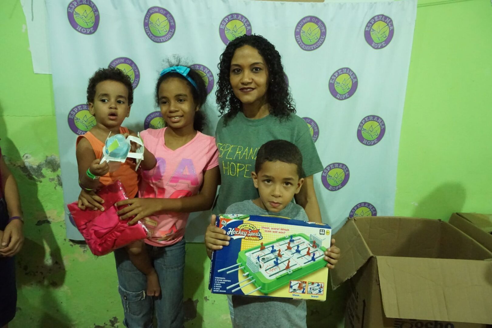 A staff and three children holding toys, standing in front of a green wall