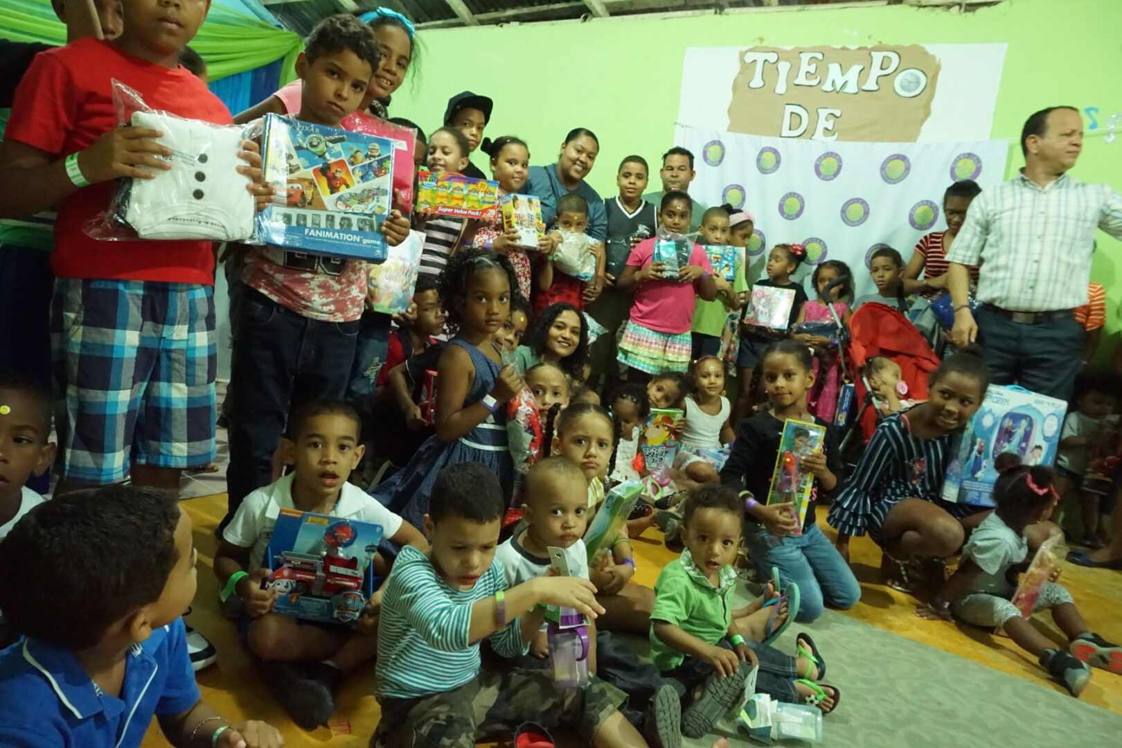 All of the children and the staff gathers in front of the room with their toys