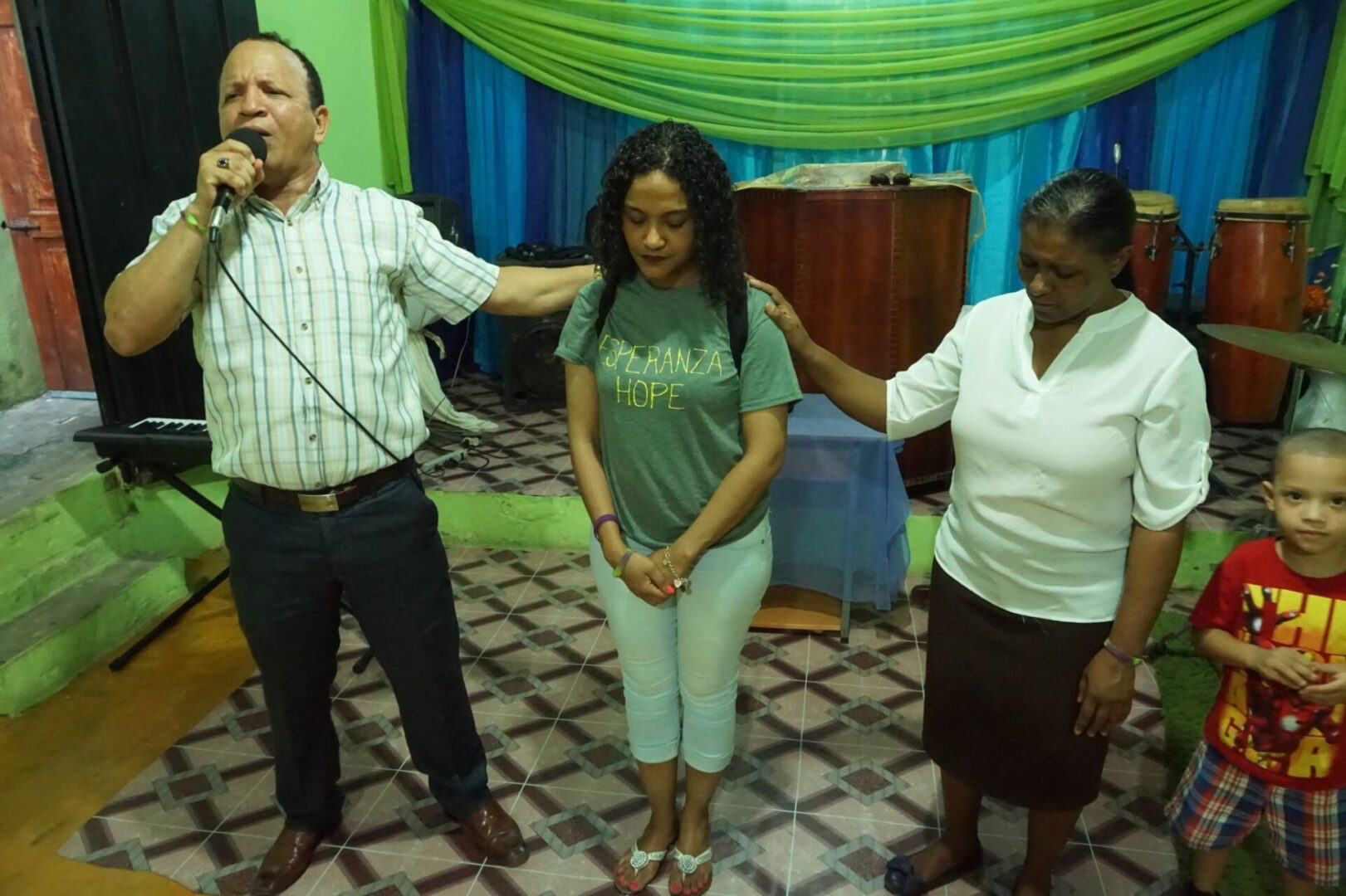 A man speaking into a mic and two women with their eyes closed