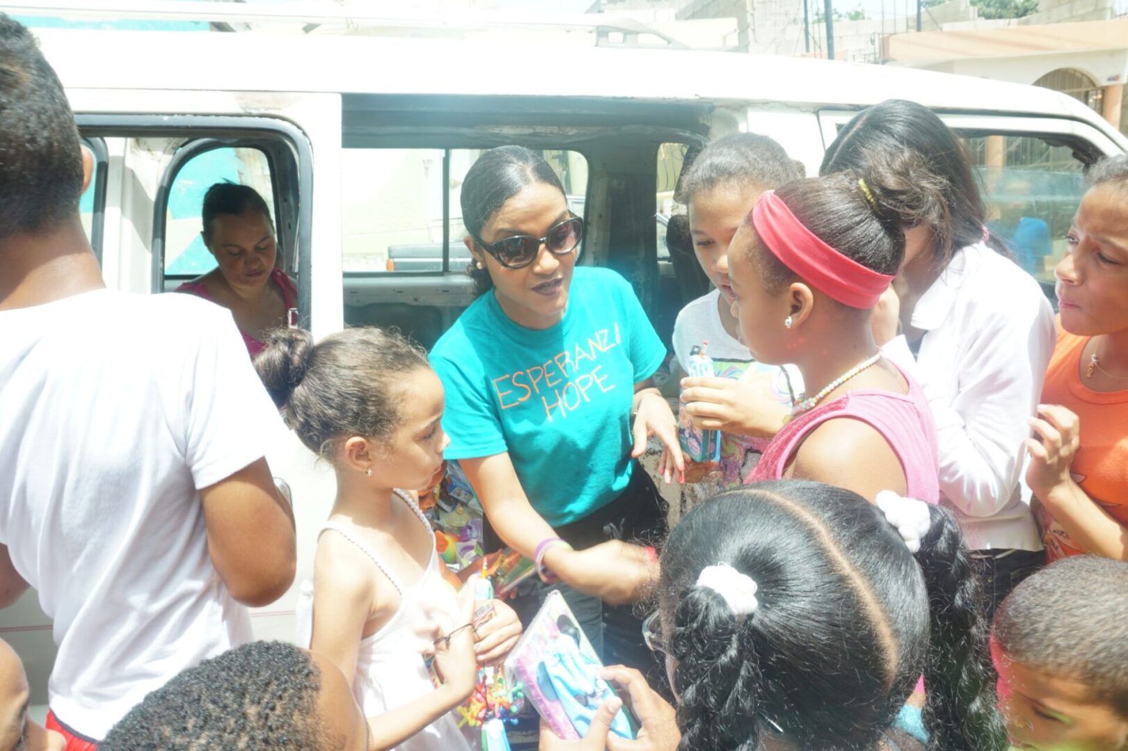 A staff in blue shirt giving out toys to girls outside the car