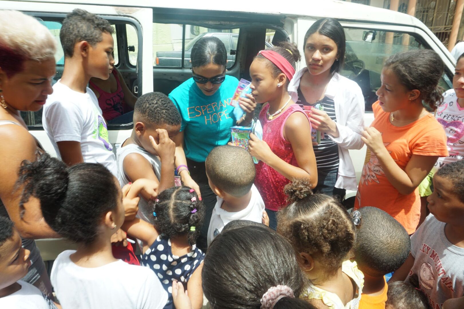 Our staff crowded by children outside the car, giving away toys