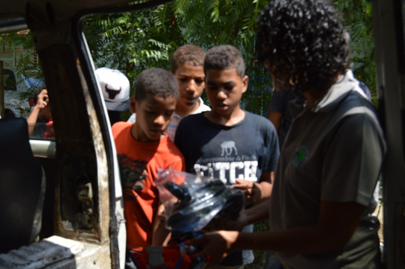 A group of older boys receiving gifts outside the car