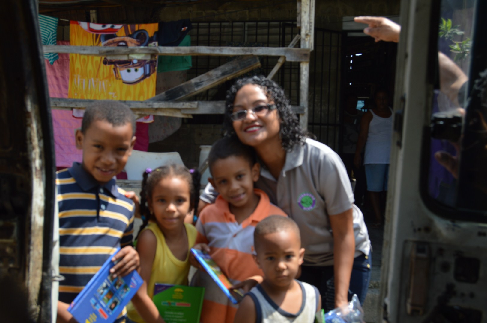 Our staff and a group of children holding books outside a house