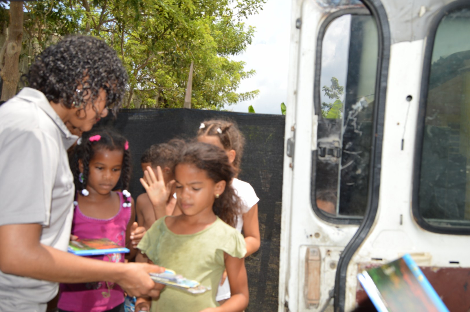 Our staff giving books to a group of children outside the car