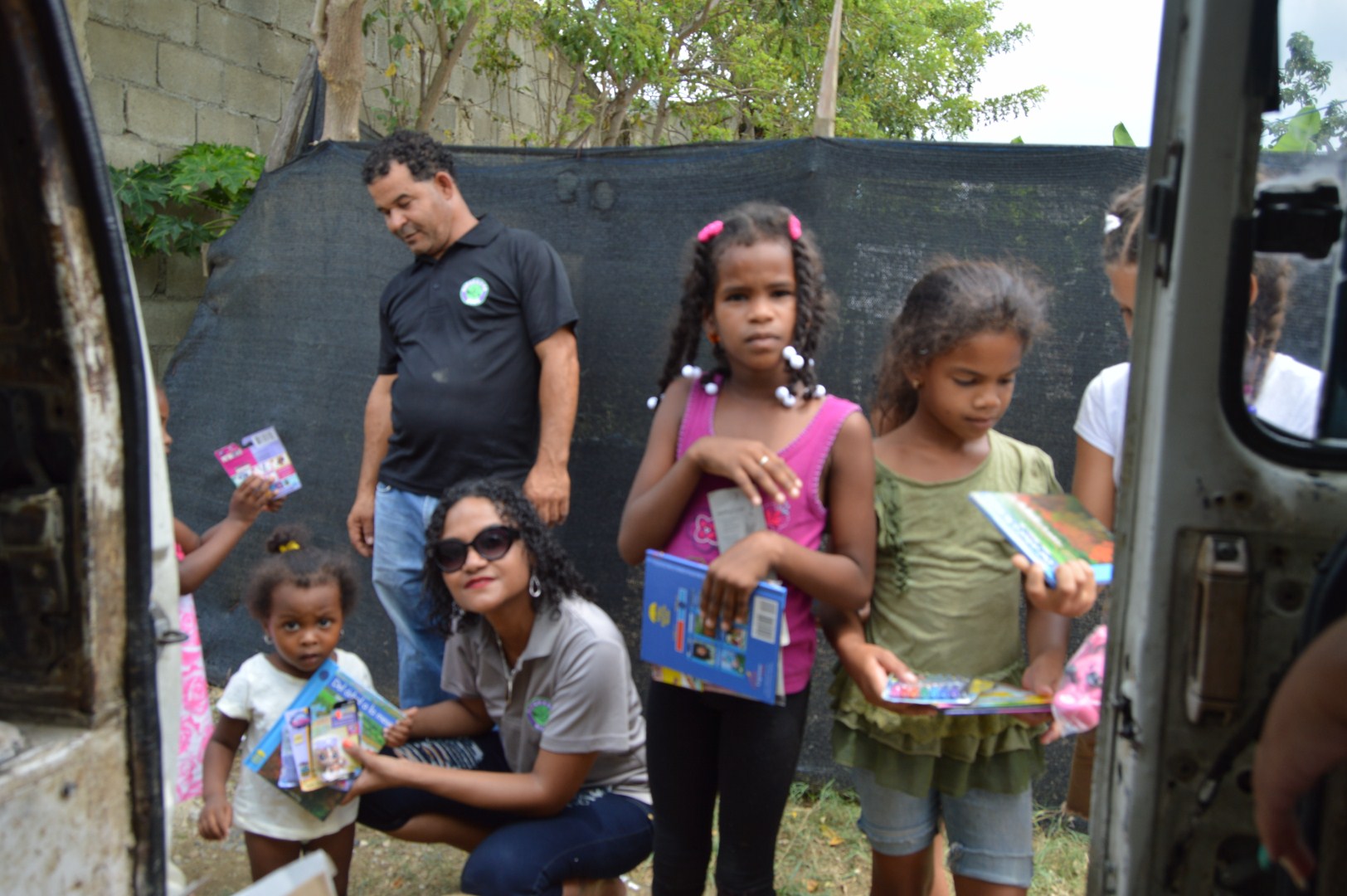 Our staff giving books to a little girl; other girls beside them